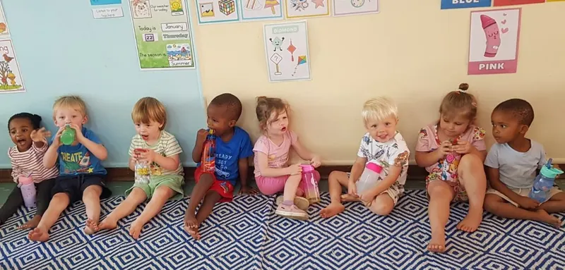 Babies and toddlers sitting together on a patterned mat in the baby centre
