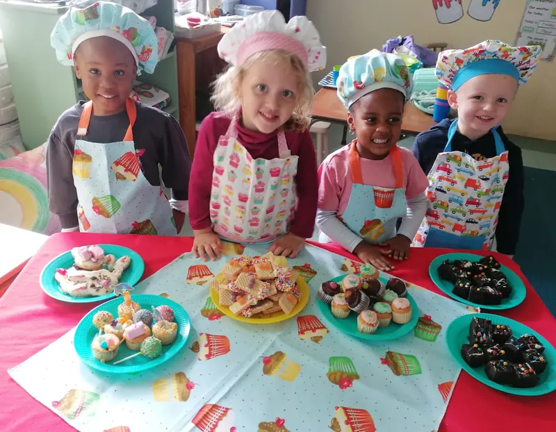 Children in chef hats and aprons decorating cupcakes