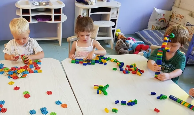 Children building with coloured blocks at a low classroom table