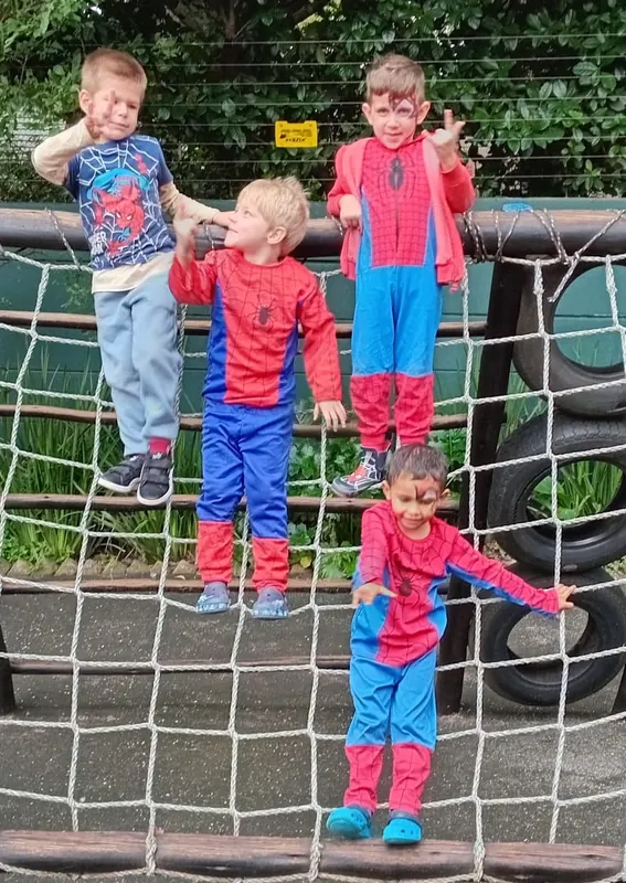 Children in superhero costumes climbing a rope net