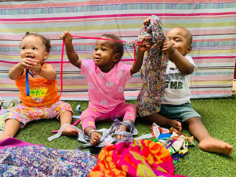 Toddlers playing with colourful ribbons and dress-up fabric