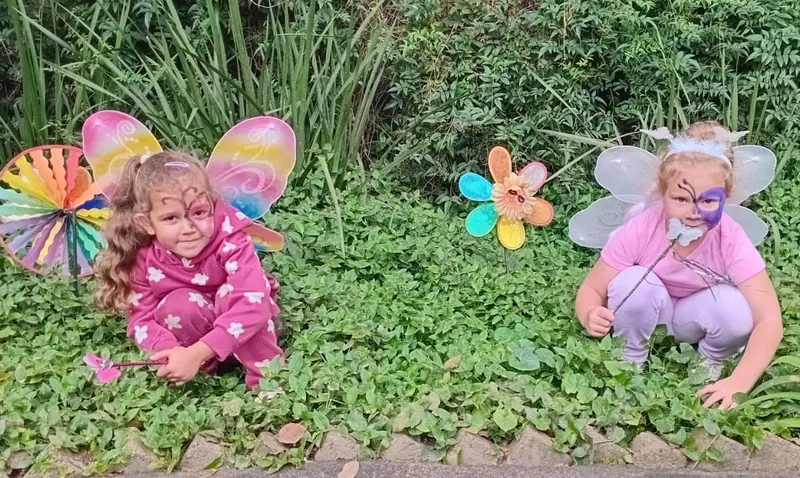 Children in fairy wings playing among the garden greenery