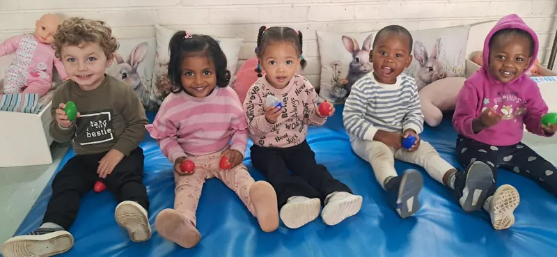 A line of children sitting together on a mat outdoors