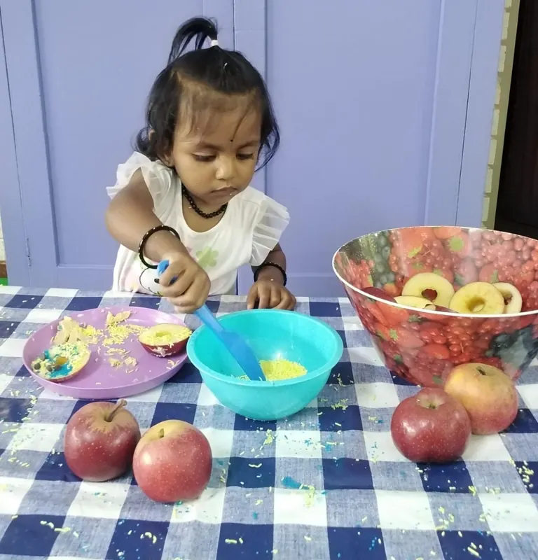 A child at a table with a bowl of fruit at snack time