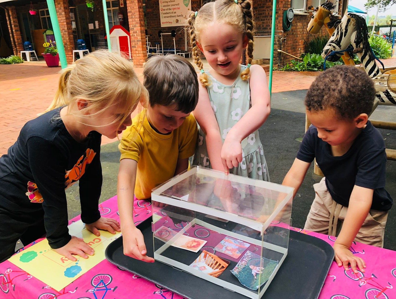 Children gathered around a tray of treasures, exploring together outdoors